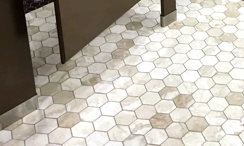 Patton’s work in a commercial restroom: the hex mosaic floor at the foot of a stall partition.