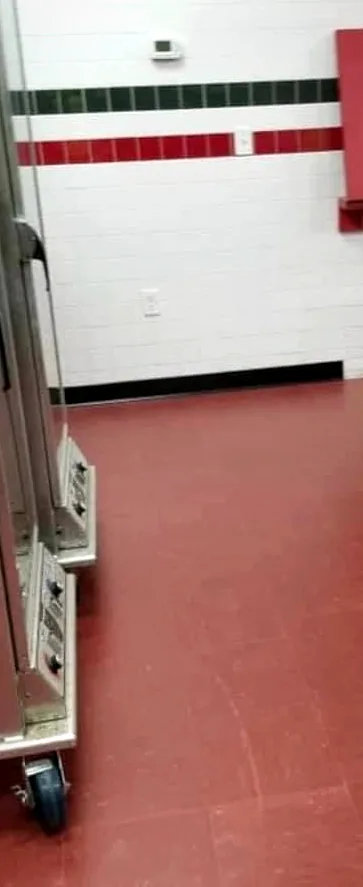 The finished kitchen: the new red floor running up to the white wall tile, with a steel cabinet at the left.