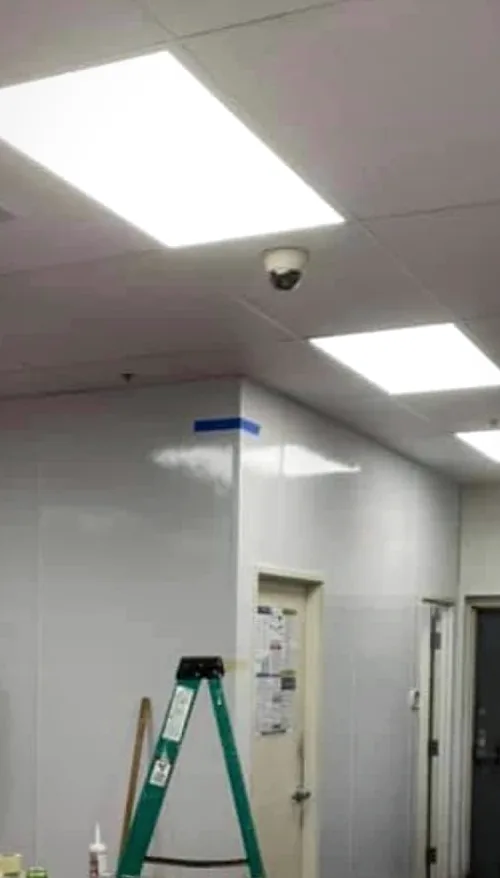 The kitchen walls covered in new glossy white panels, with a door, ceiling lights and a stepladder still up.